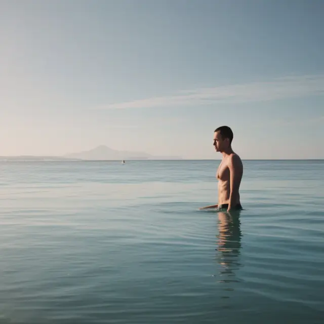 Two swimmers gracefully swim in a serene pool amidst the calming backdrop of an undisturbed ocean, emphasizing efficient progress and effective resource utilization